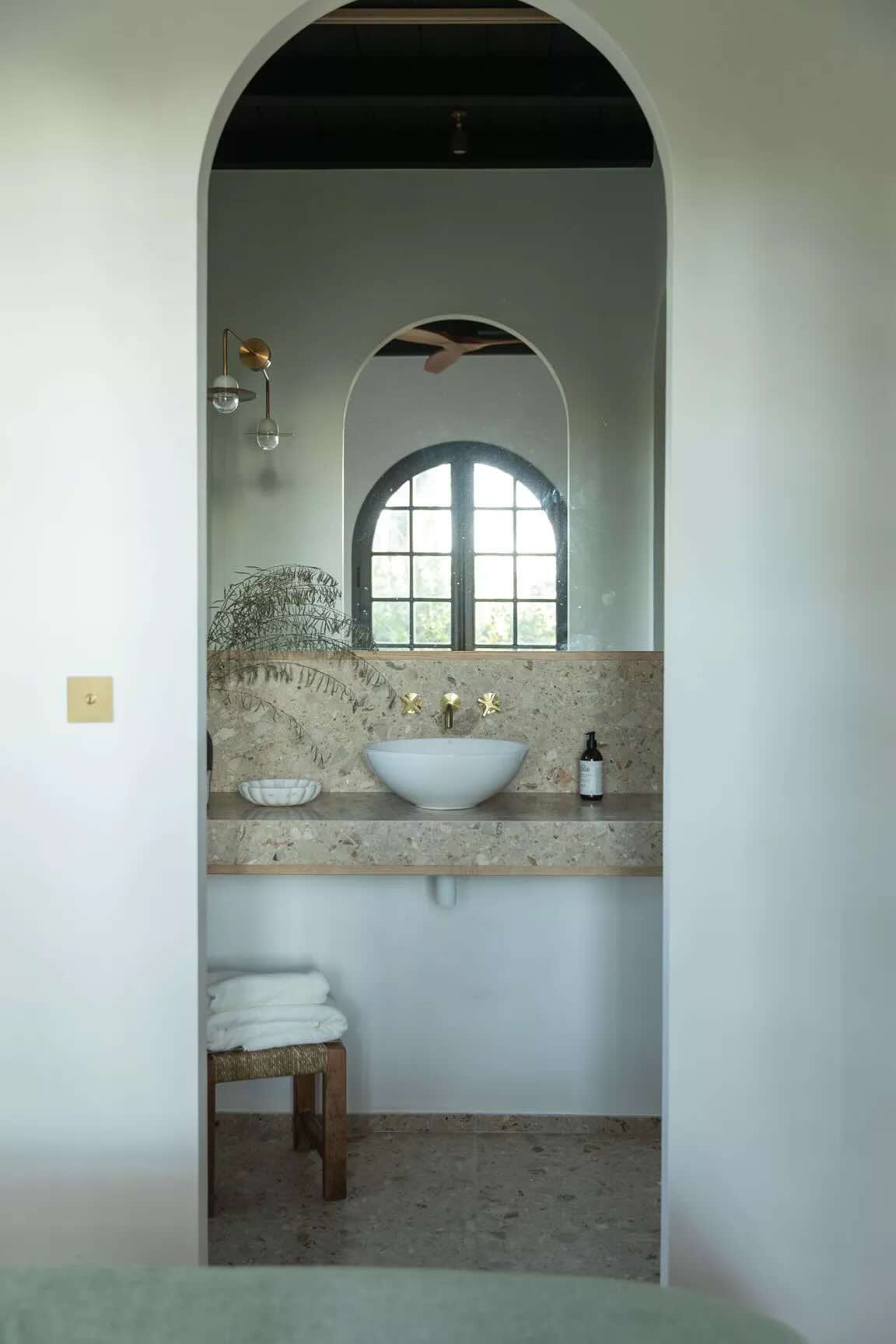 Salle de bain sous arche blanche, vasque en pierre et robinetterie en laiton